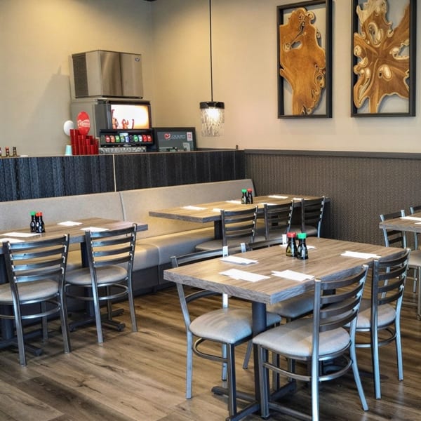 Empty restaurant dining room with tables, chairs, booths, and a soda fountain in the background.