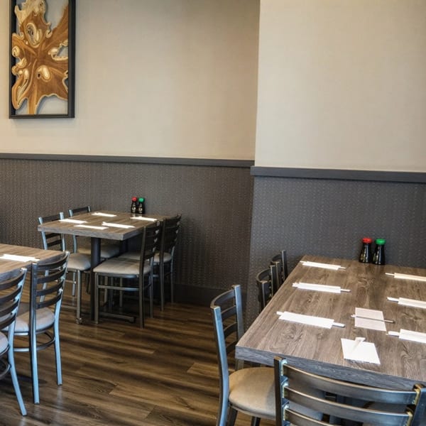 Empty dining room with wooden tables, metal chairs, and a textured dark gray wainscoting.