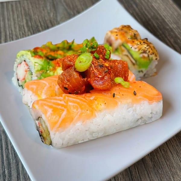 A white rectangular plate holds three different types of sushi rolls on a wooden table.